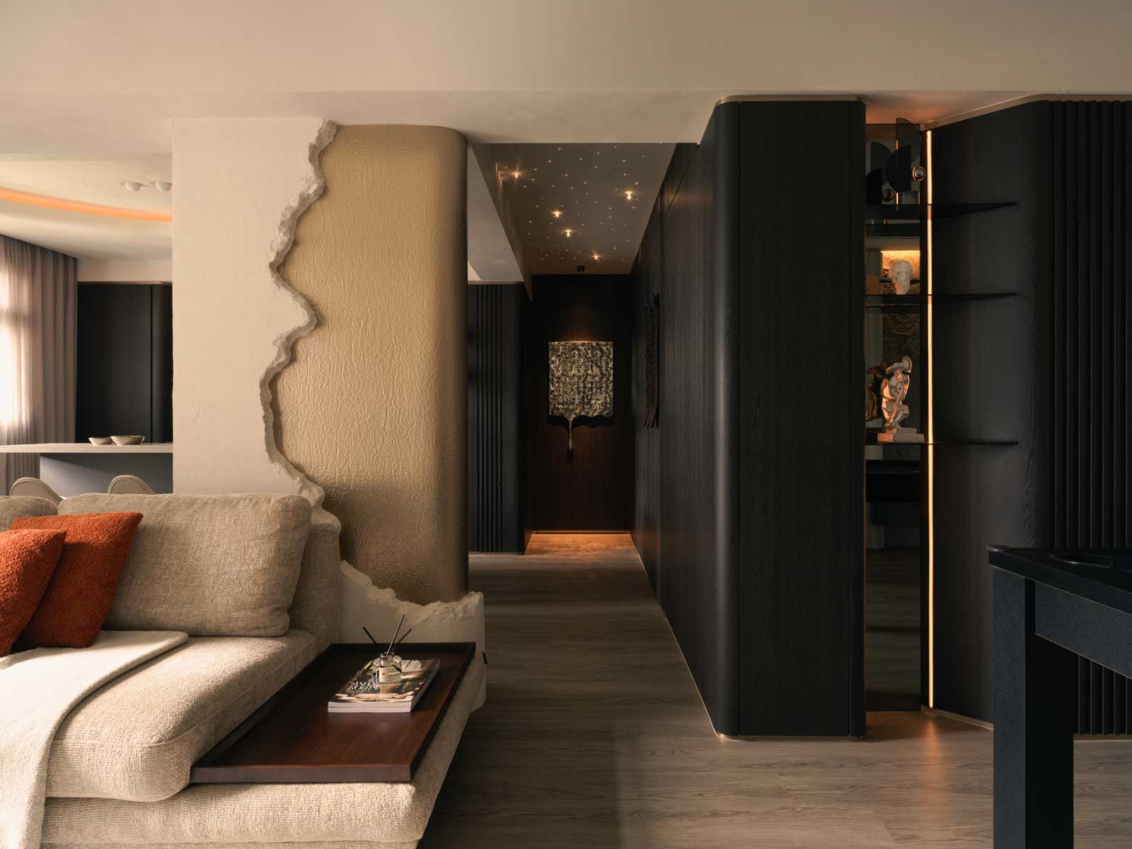A striking feature wall—half raw plaster, half gilded—injects sculptural flair and subtle contrast into the soft, tonal interior