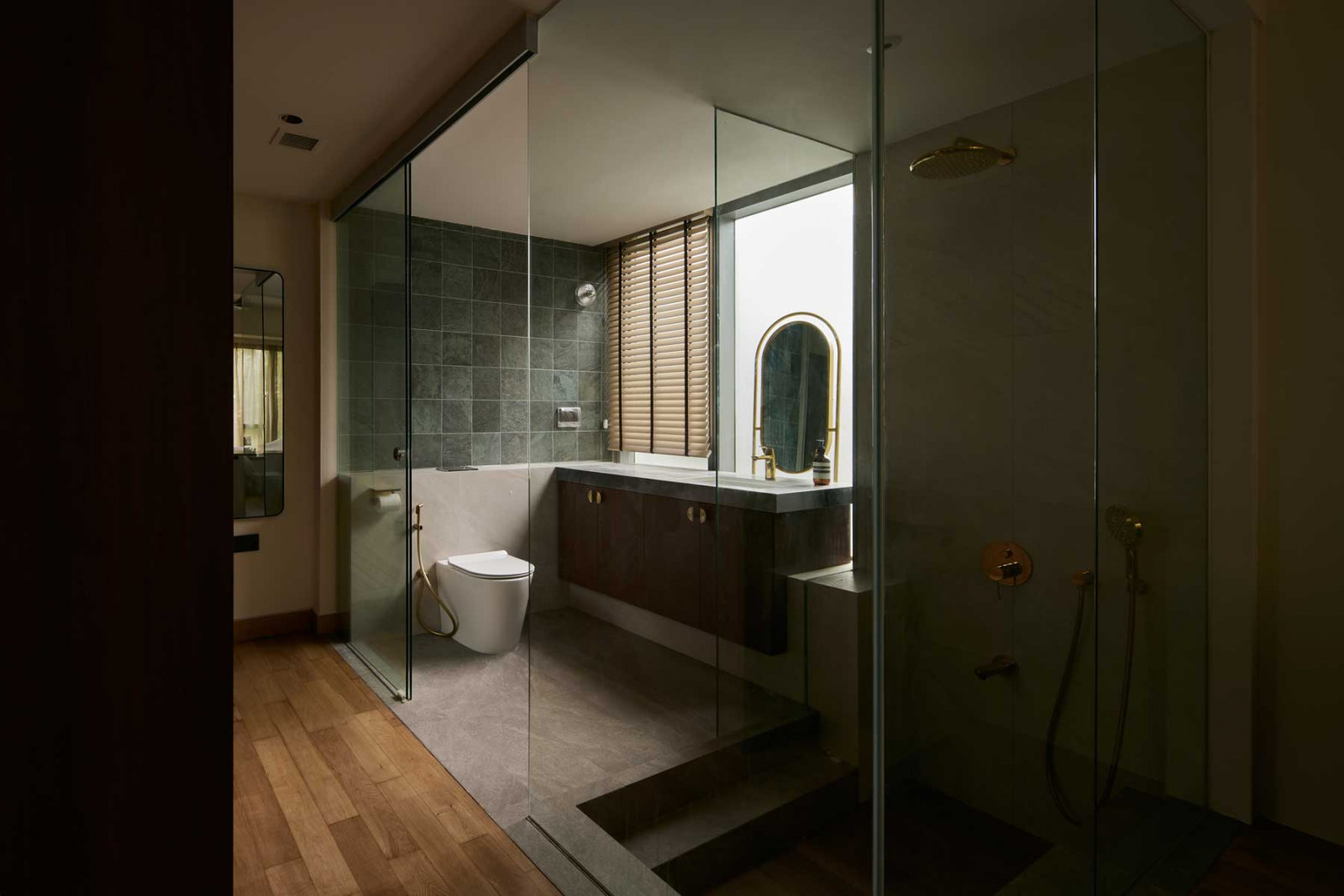 The spa-like master bathroom features a step-down shower, rich stone textures and soft lighting—fostering calm and relaxation