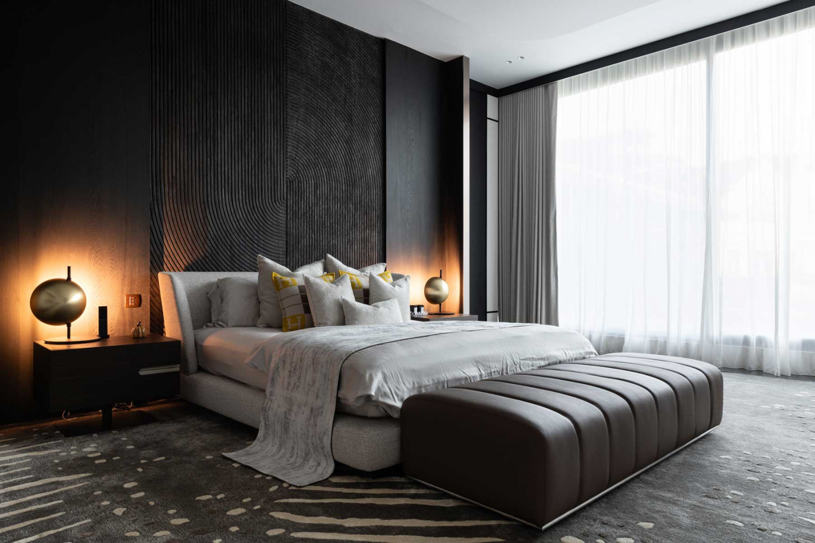 The master bedroom exudes a hushed, intimate mood with its dark, cocooning palette