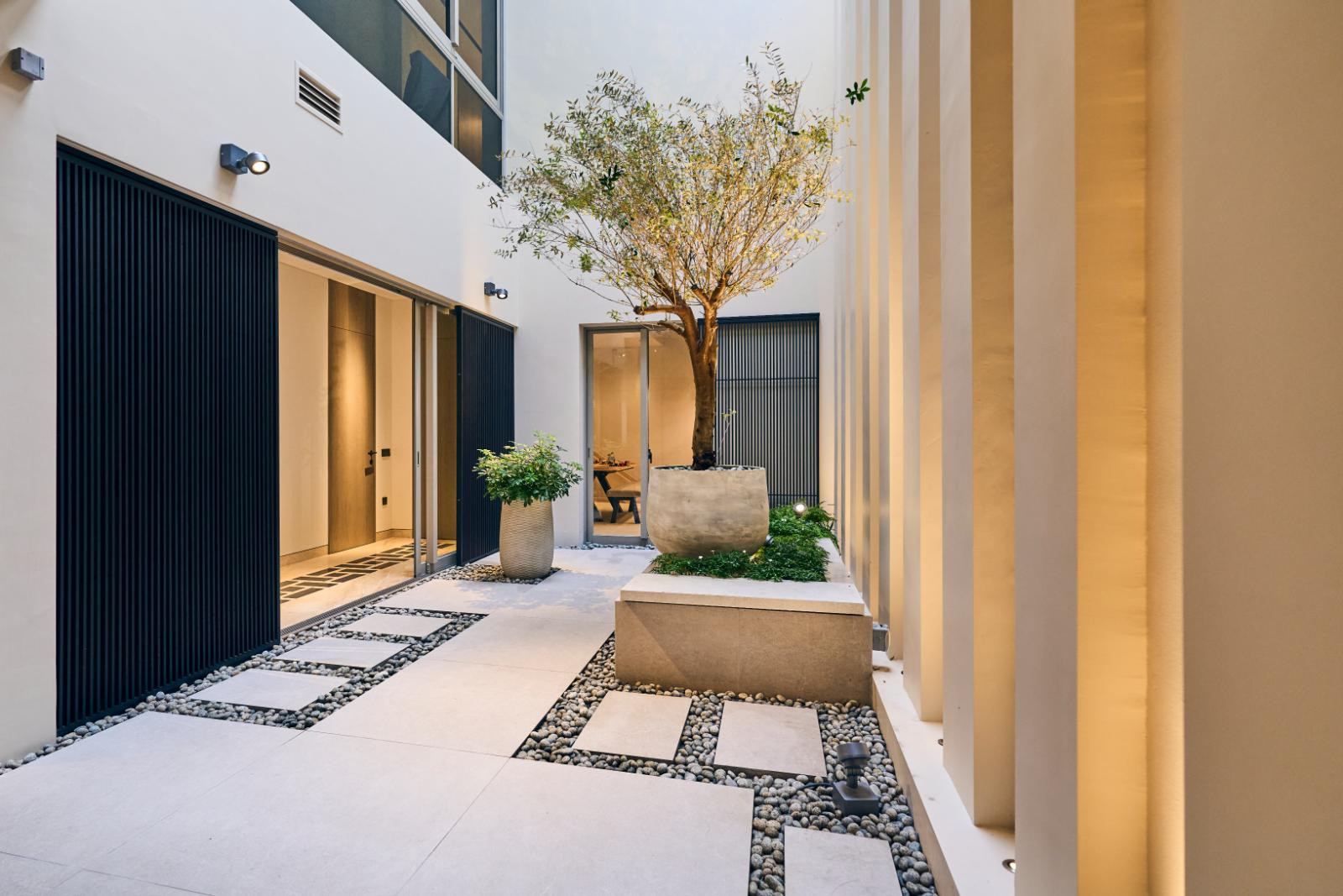 Ribbed wall pillars, a rectangular patio and vertical iron slatted shutters in the courtyard set the tone for the language of lines