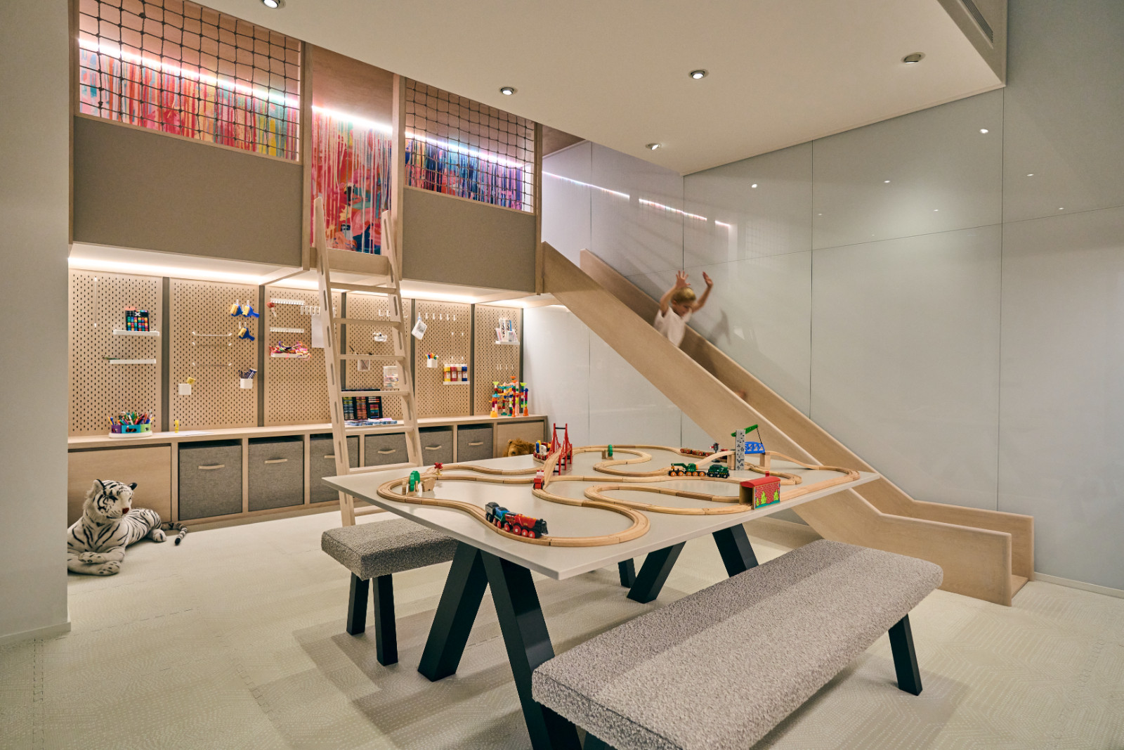 A view of the townhouse’s playroom, featuring bespoke paint splattered wallpaper, a slide and floor to ceiling storage