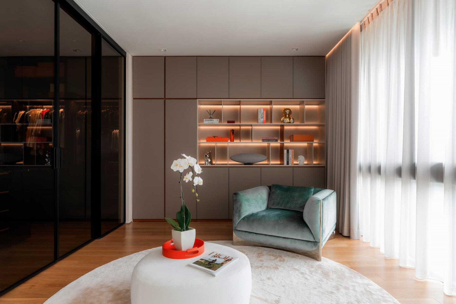 A view of the master suite comprising the sleeping area, a light-toned sitting area and the wardrobe in a contrasting dark palette