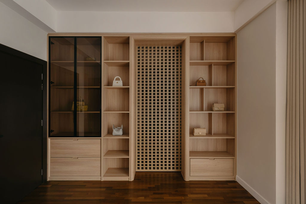 The walk-in wardrobe has a full wall of wood-textured built-in cabinetry combining open shelving, lattice-fronted panels, and glazed display sections for the homeowner’s handbag collection