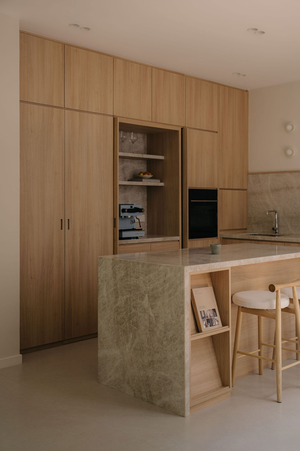 The dry kitchen, with a green quartzite island and floor-to-ceiling wood-textured laminate cabinetry