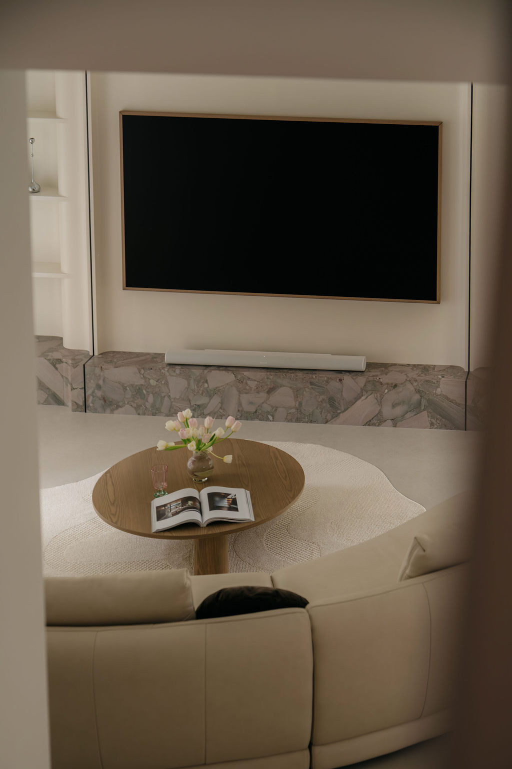A closer view of the TV wall, with the Palladium Sage quartzite base and the Nicchris coffee table on a shaped rug in the foreground