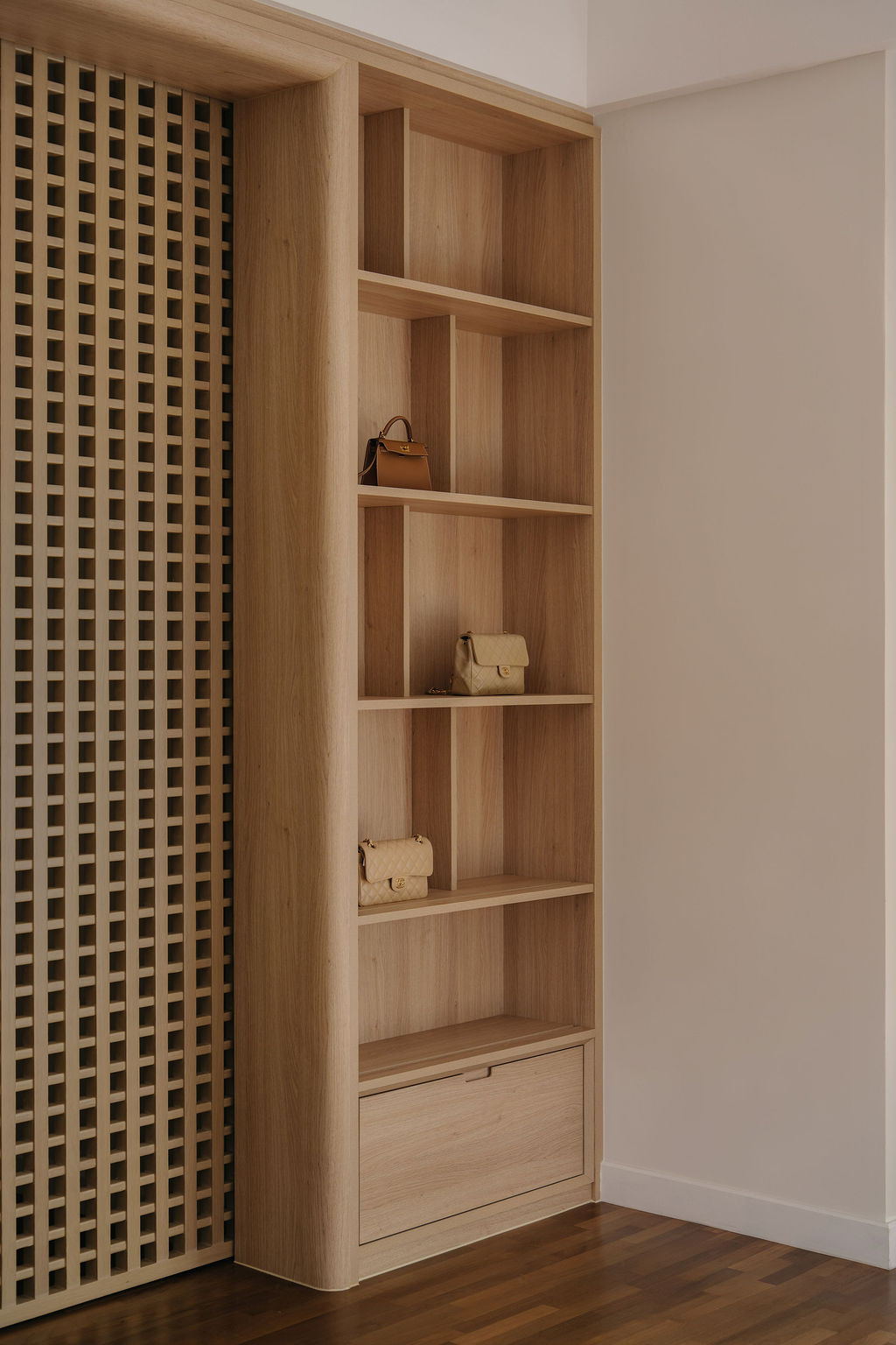 A dressing area fitted with a lattice-fronted wardrobe panel and open shelving for displaying the homeowner’s handbag collection