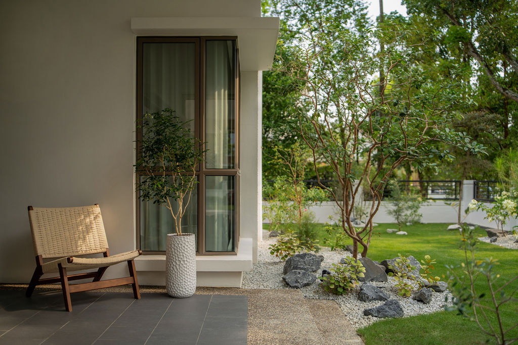 The rear garden terrace, with a woven lounge chair beside a tall planted pot