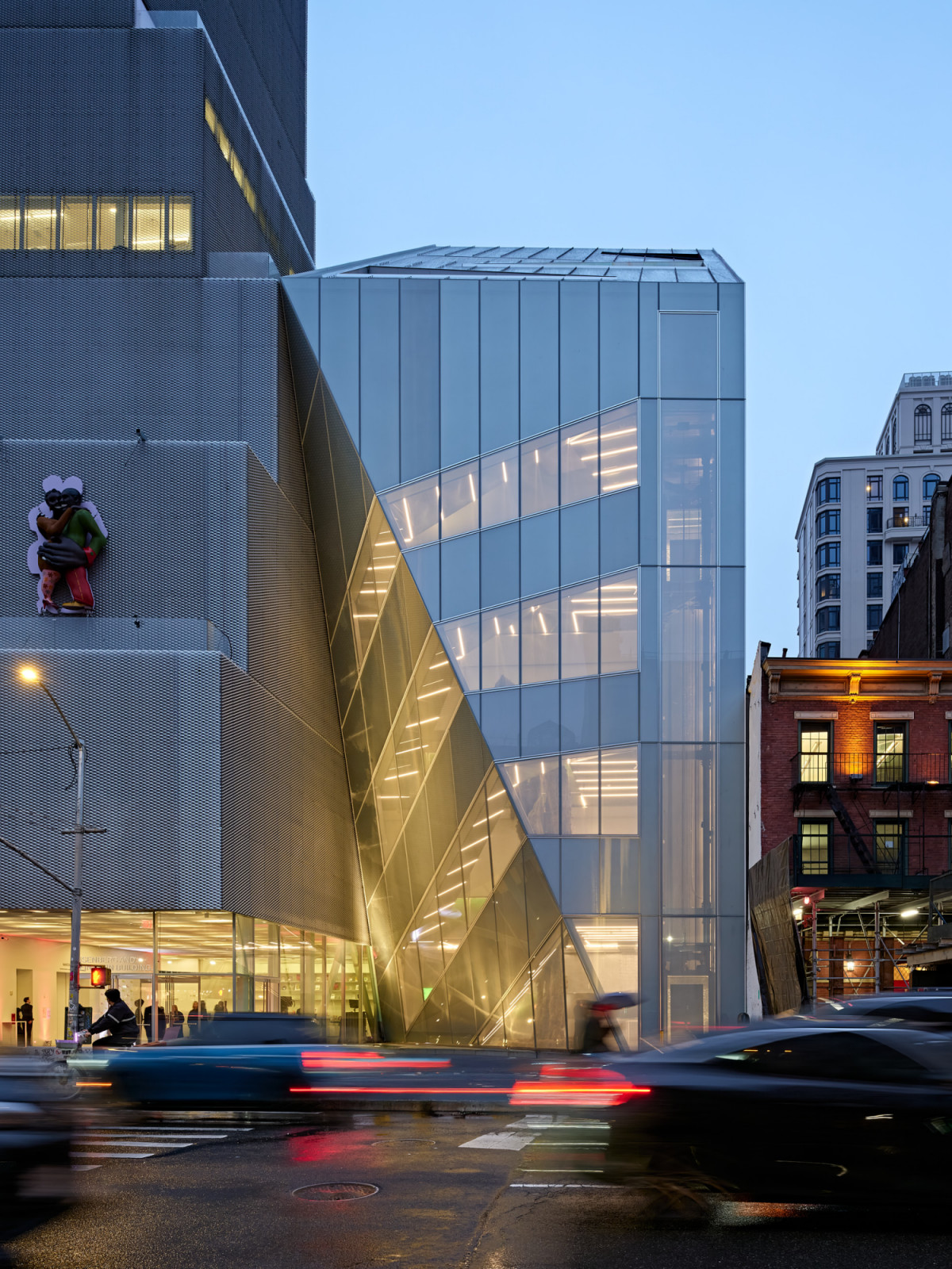 The ground-level entrance of the OMA addition, where diagonal glass planes form the atrium stair facing the Bowery (Photo: New Museum)