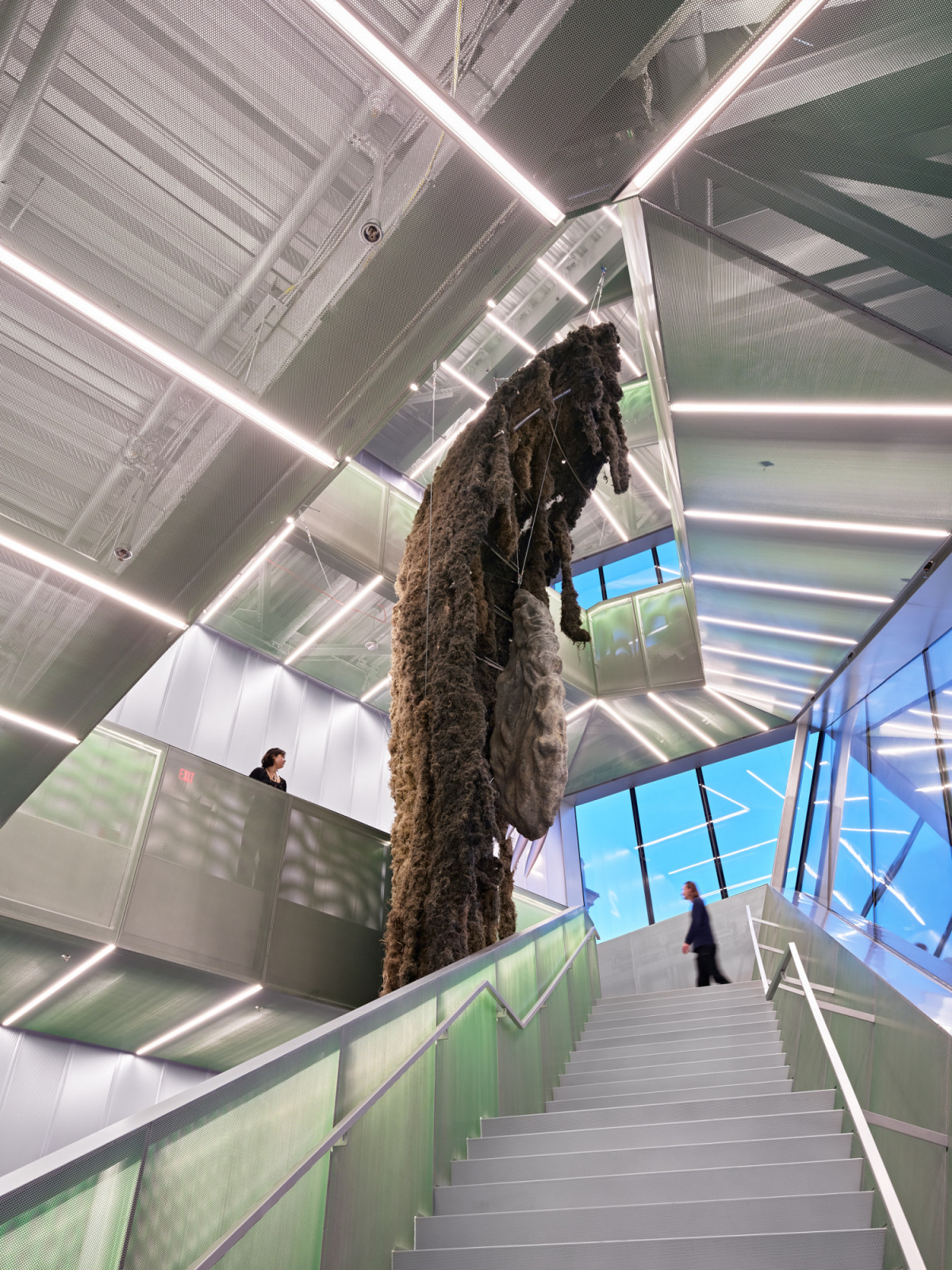 The atrium stair of the OMA addition, with a large suspended installation occupying the full height of the space (Photo: New Museum)