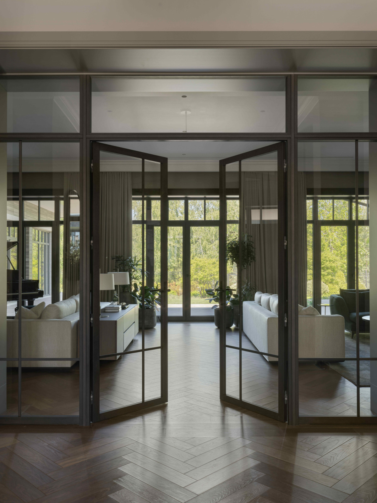 The sequence leads to the generous living room, anchored by parquet flooring by Bonum