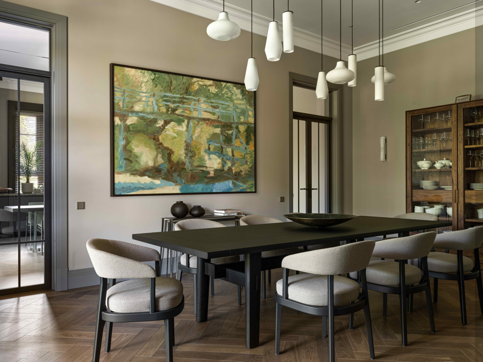 The dining room marked by a striking wall-mounted artwork and a sculptural chandelier by Panzeri, lending a deeply personal character