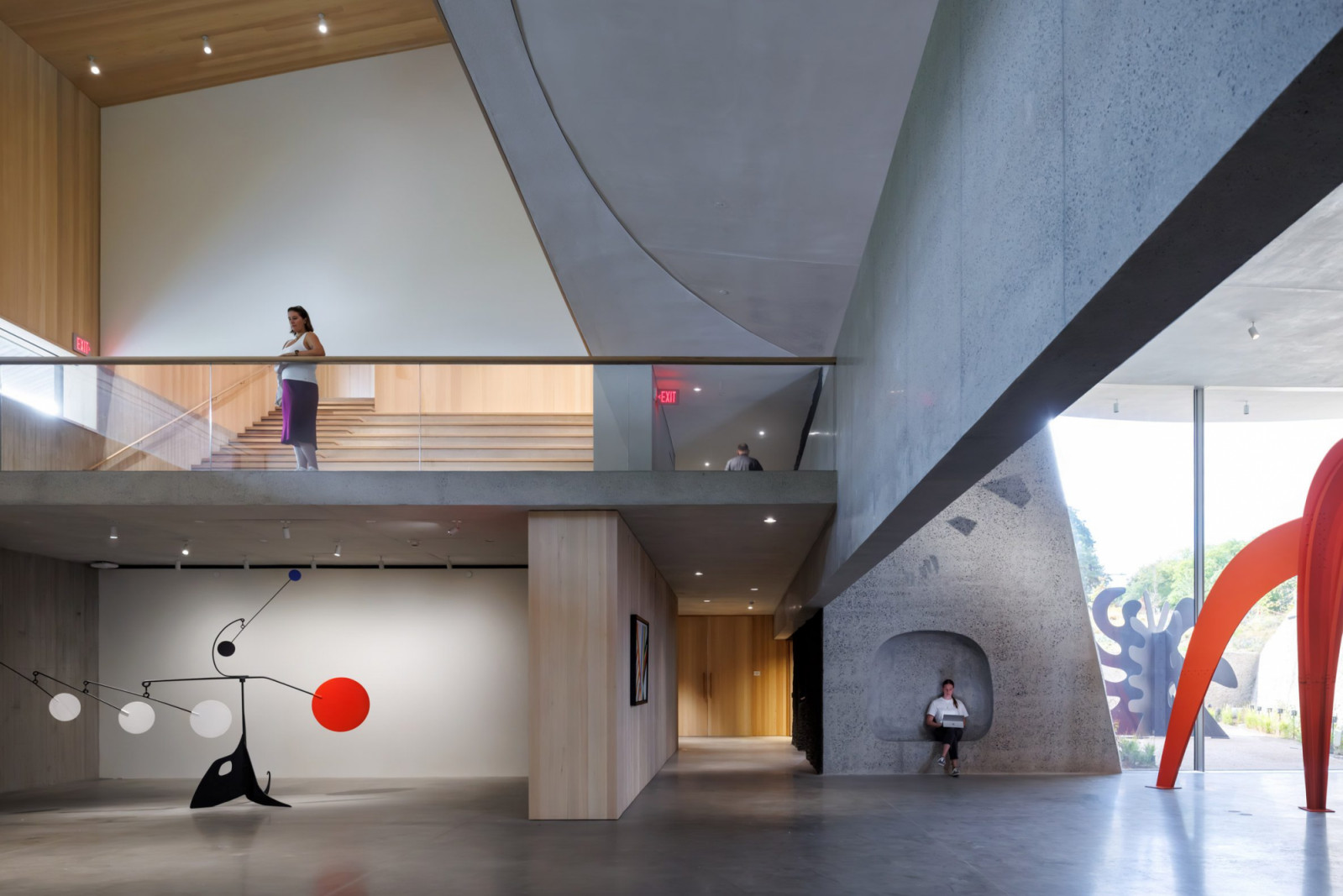 The interior of Calder Gardens, showing the Highway Gallery mezzanine level with its interplay of warm timber, curved concrete, and double-height space where a Calder mobile is displayed on the lower level (Photo: Iwan Baan/2025 Calder Foundation, New York)