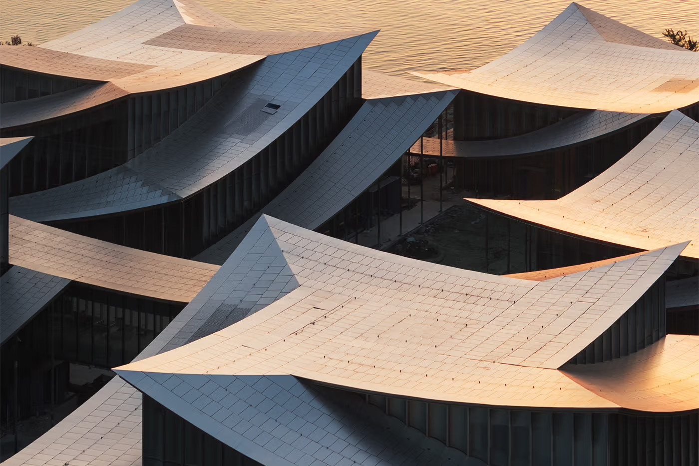 Detail of the Suzhou Museum of Contemporary Art's ribbon-like stainless steel roof at dusk, its conical curves catching the warm tones of the setting sun over Jinji Lake (Photo: BIG)