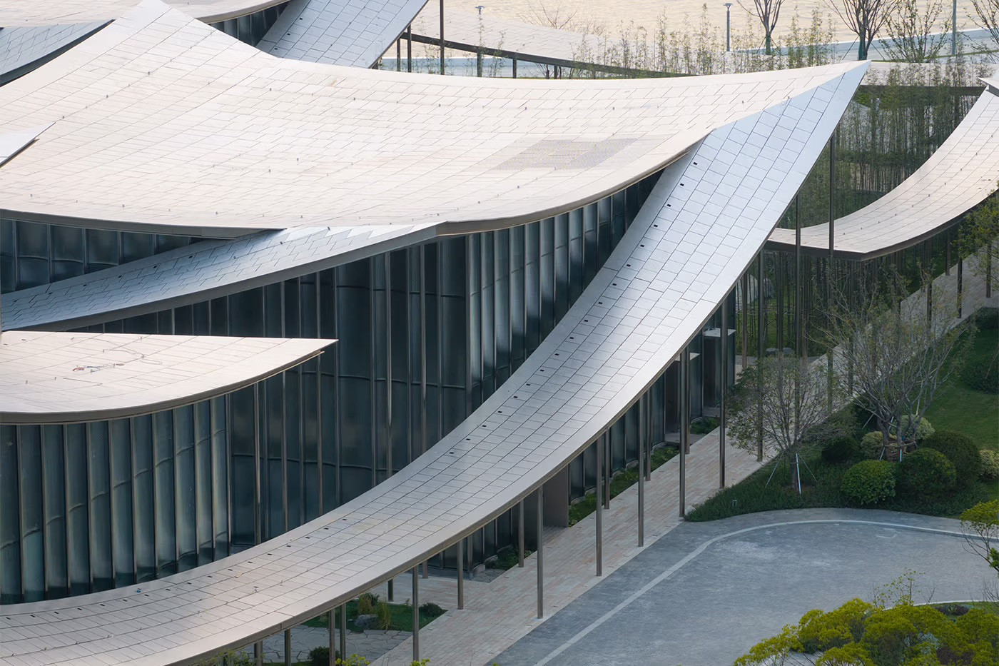 Close-up of the Suzhou Museum of Contemporary Art’s curved eaves and glazed facade, showing the lang-inspired covered walkway running between pavilions (Photo: BIG)