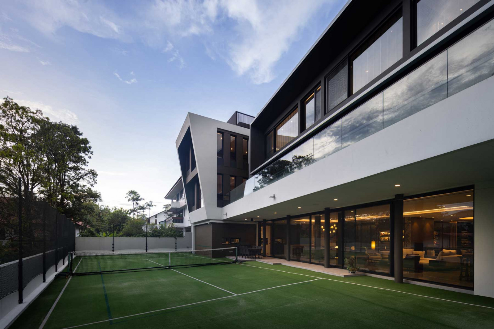 The lush tennis court helps to visually extend the already expansive living and dining areas even further