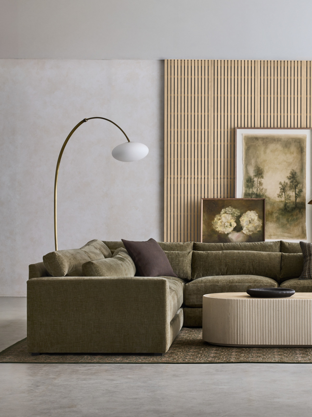 The Retreat Grande Sofa anchors the space with its extra-wide arms and plush yet supportive cushions, offering a clean-lined sanctuary for lounging. Complementing its soft proportions, the Kahn Coffee Table introduces a sculptural element with its ribbed off-white concrete base and inset oak top (Photo: courtesy of Crate and Barrel)