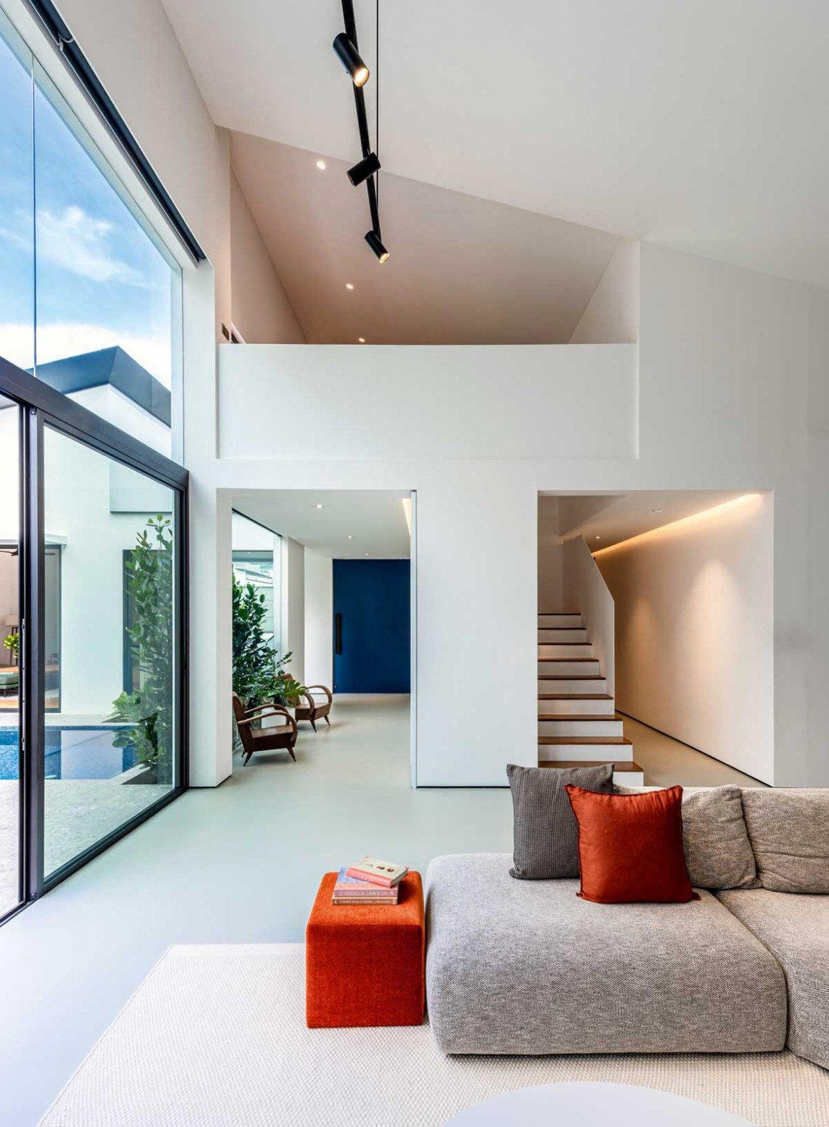 The Swiss Club Lane residence’s double-height living room opens to a lofted upper level
