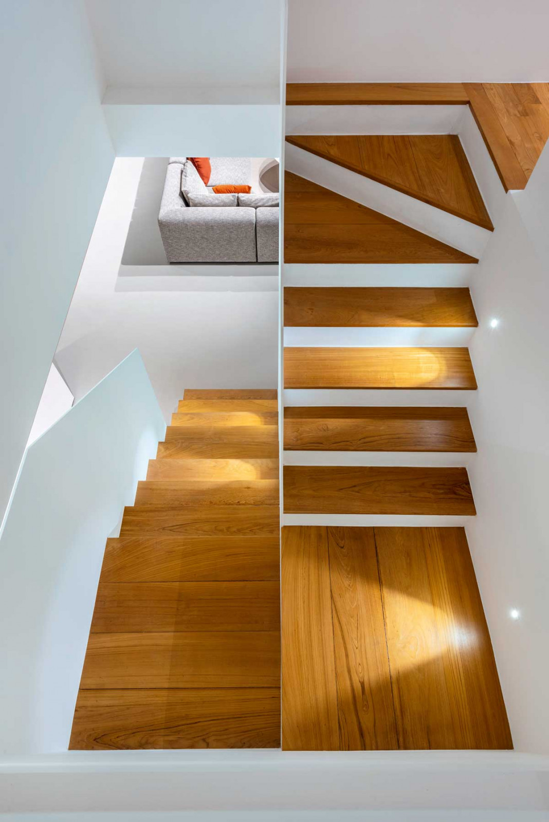 The staircase in the same home pairs crisp white planes with warm timber treads