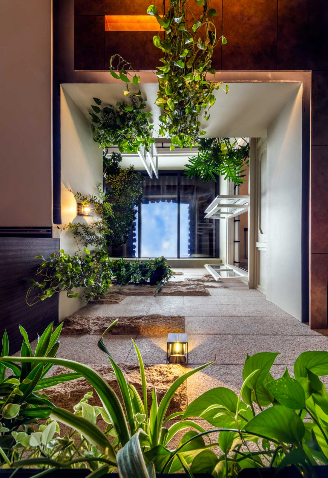 A view up the lightwell at the same project reveals the sky framed by greenery planted throughout the levels