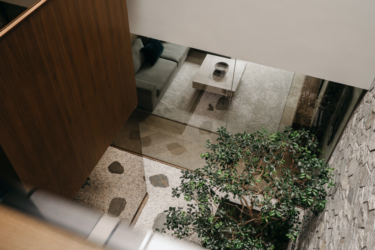 Looking down from an upper level into the sunken courtyard, with the living room visible through the glass wall beyond