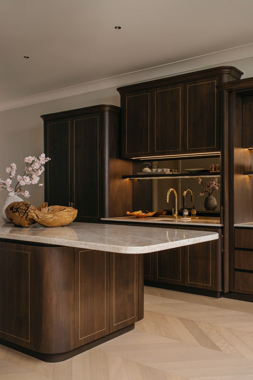 The wet kitchen island, with a rounded marble top and dark walnut cabinetry detail