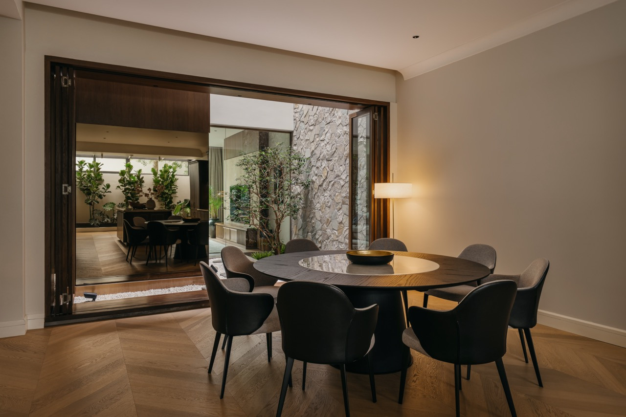 The dining area opens directly onto the sunken courtyard via sliding timber-framed doors