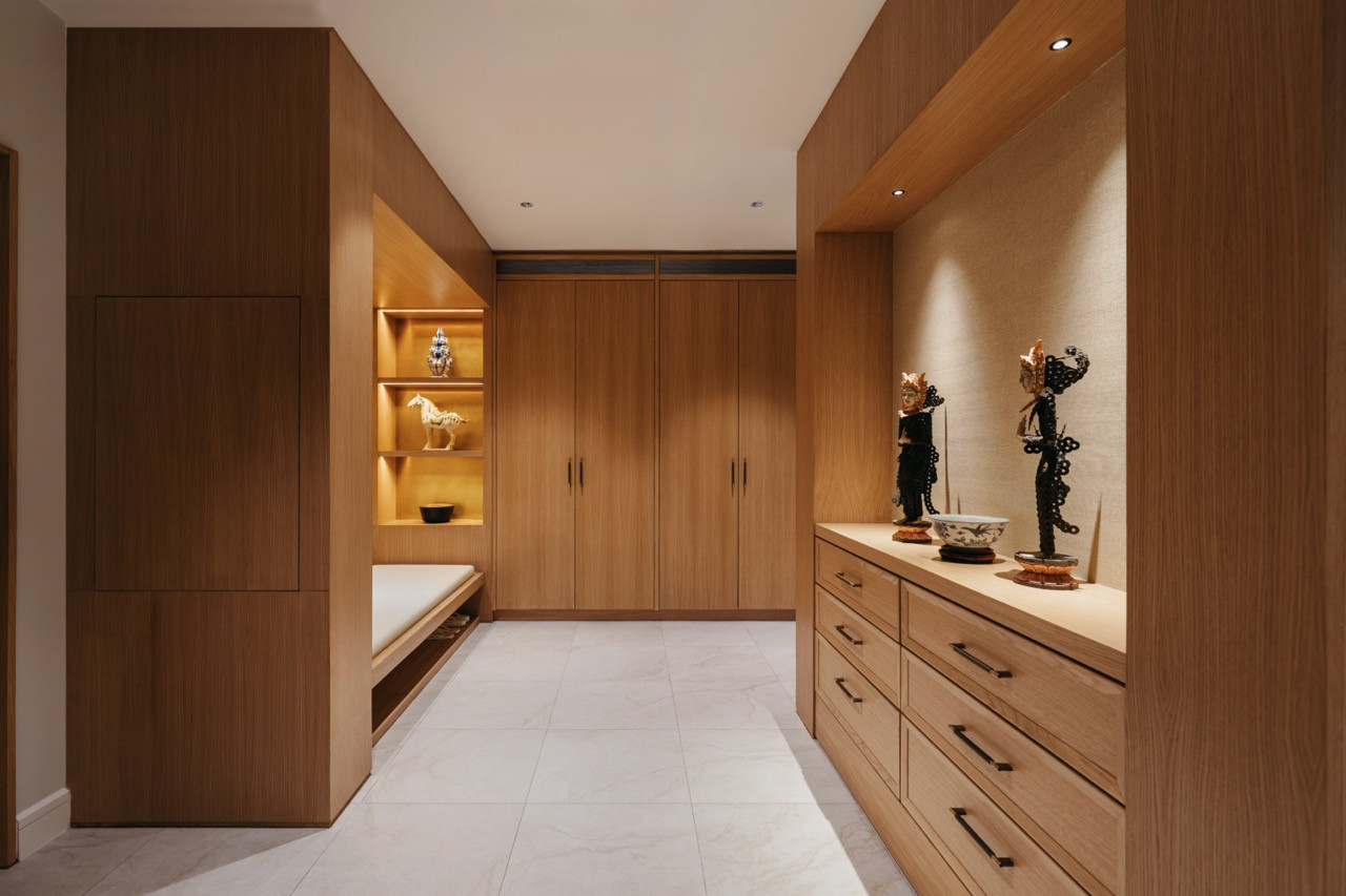 The foyer, lined with warm oak joinery, lit display niches and a built-in bench