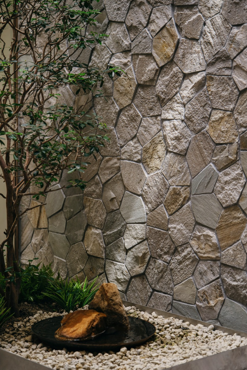 A close-up of the courtyard’s stone-clad wall, water feature and planting bed, showing the varied texture and tonal range of the polygonal stonework