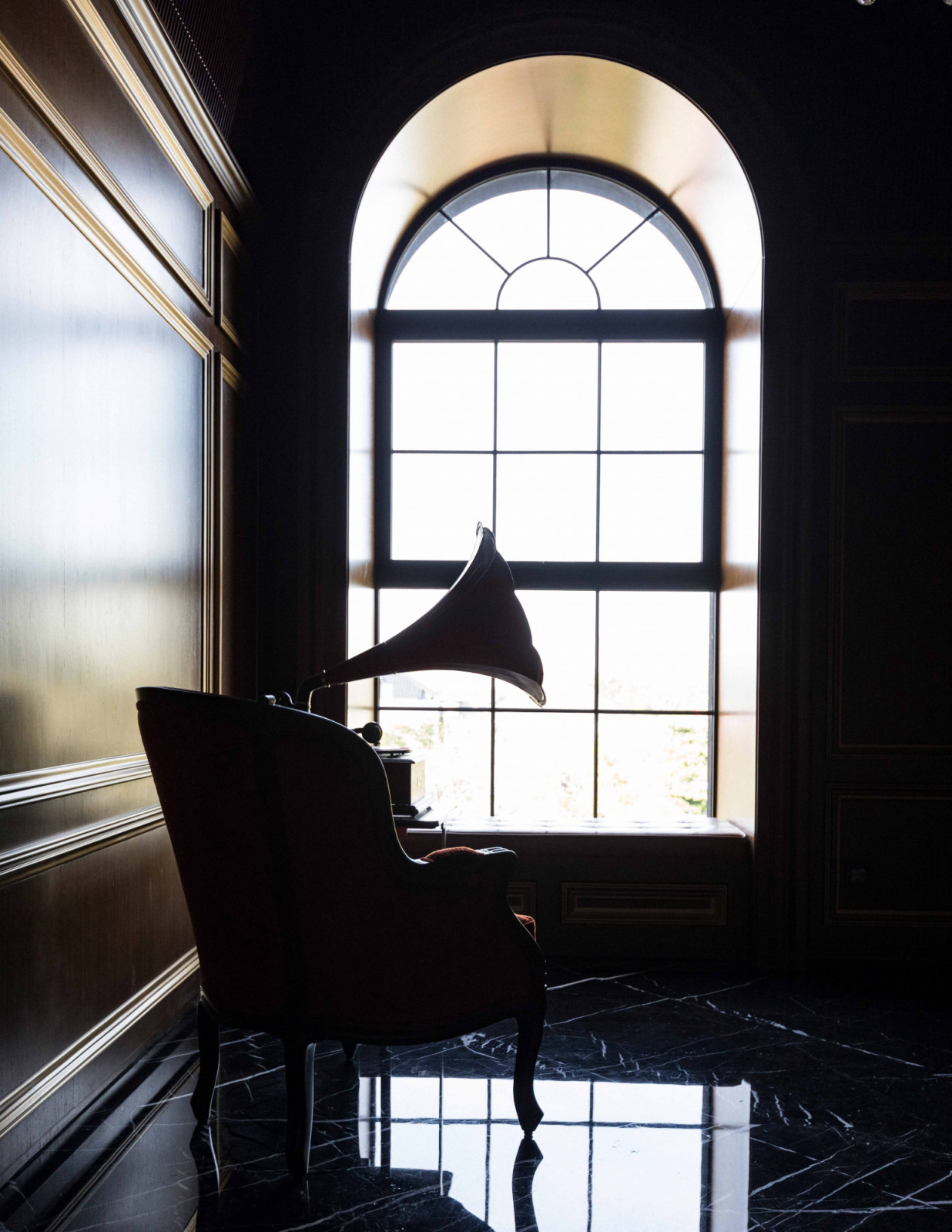 An arched window frames the silhouette of an armchair and a classic gramophone at The Continental
