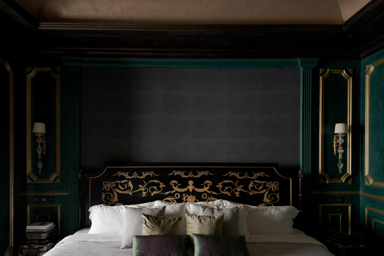 Gilded motifs and deep green panelling frame the bed