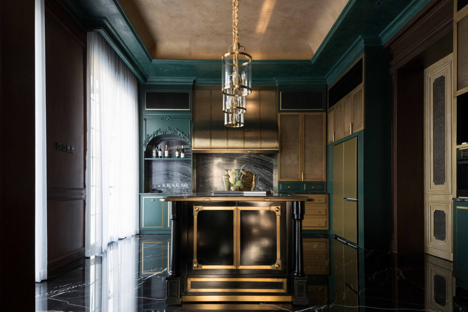 The pantry pairs deep green cabinetry with brass accents and a marble island