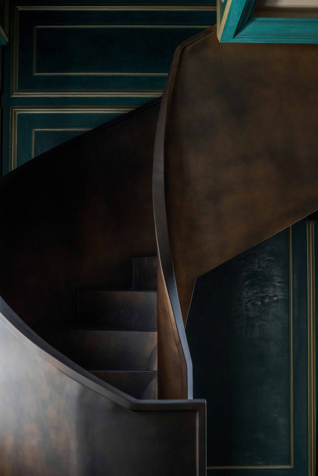 A dark wood staircase curves through the levels of The Continental