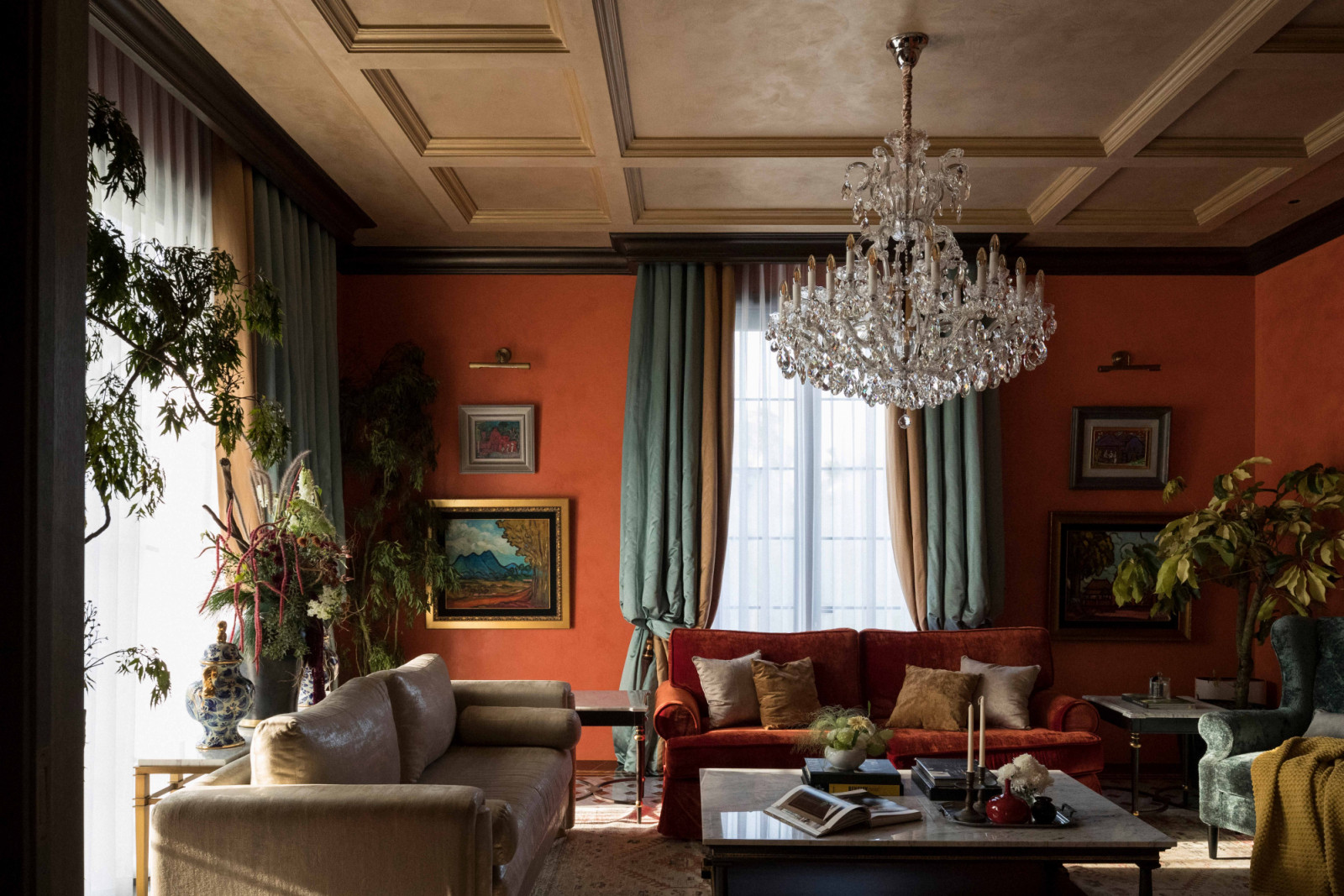 The living room sets the tone with orange walls, green draperies and classical mouldings, evoking an old-world salon where antiques and furniture from the Jaya Ibrahim collection create a layered sense of glamour