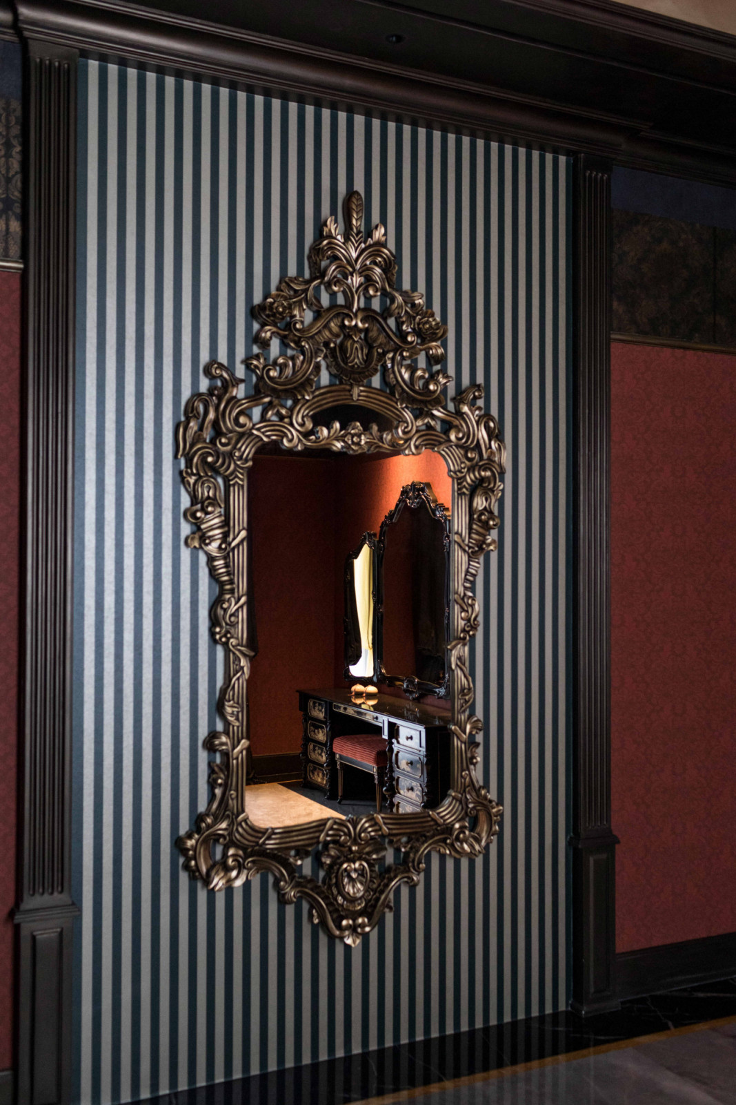 A gilded mirror on striped wallpaper at The Continental juxtaposes old-world and new-world glamour