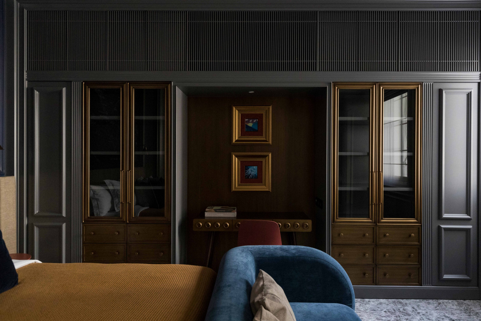 Dark panelling, brass-framed cabinetry and a writing desk imbue the study with a quiet sophistication