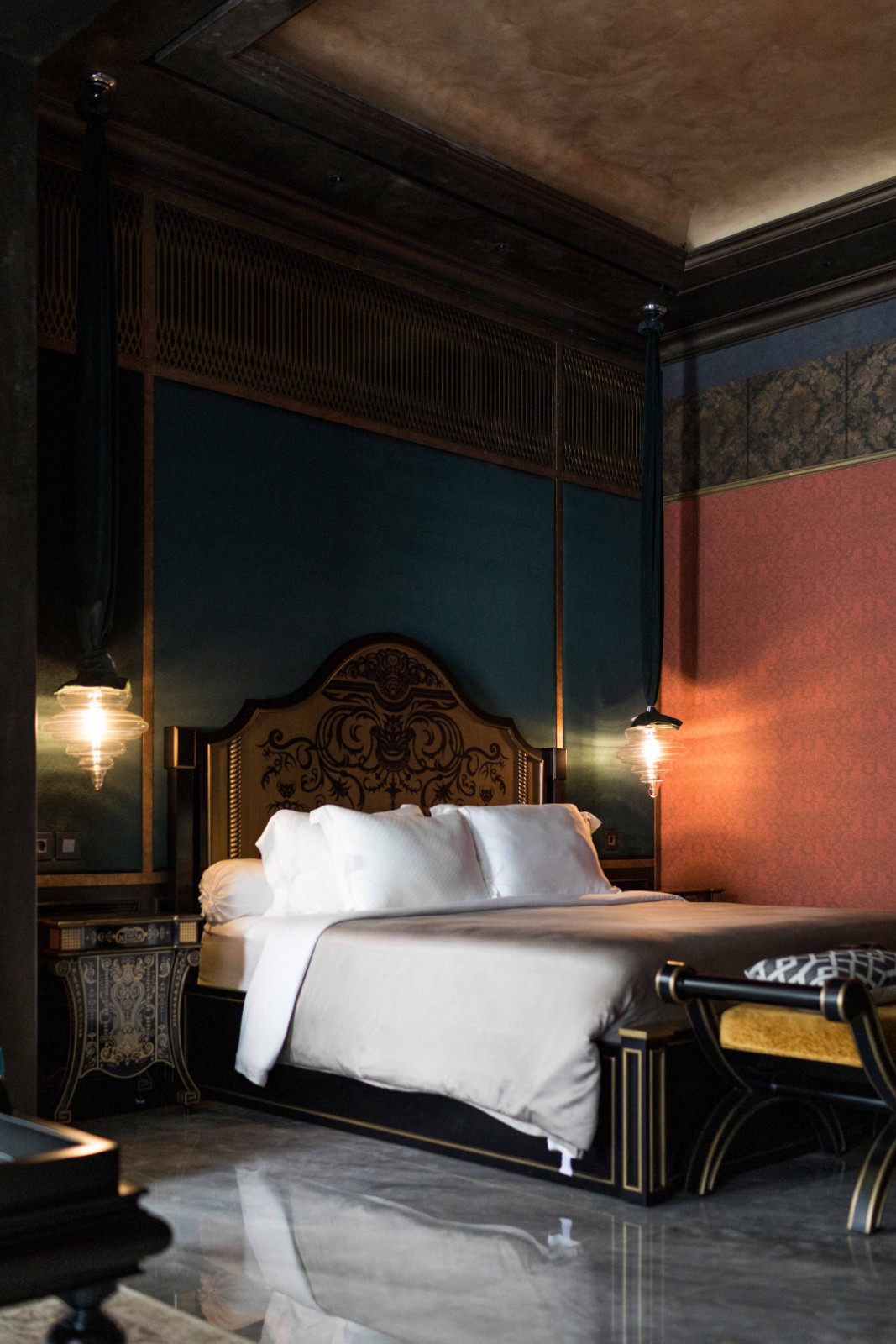 Deep teal walls frame the bed, flanked by pendants from Lasvit’s Neverending Glory series that mimic historical theatre chandeliers