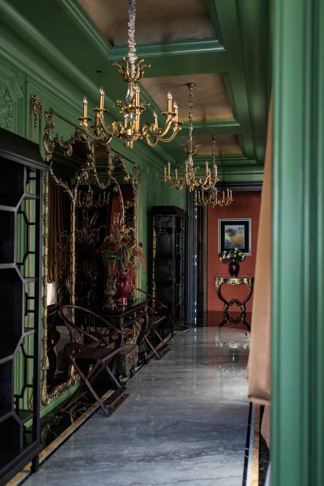 Green panelled walls, mirrored panels and brass chandeliers give this corridor a subtle reminiscence of Versailles’ Hall of Mirrors