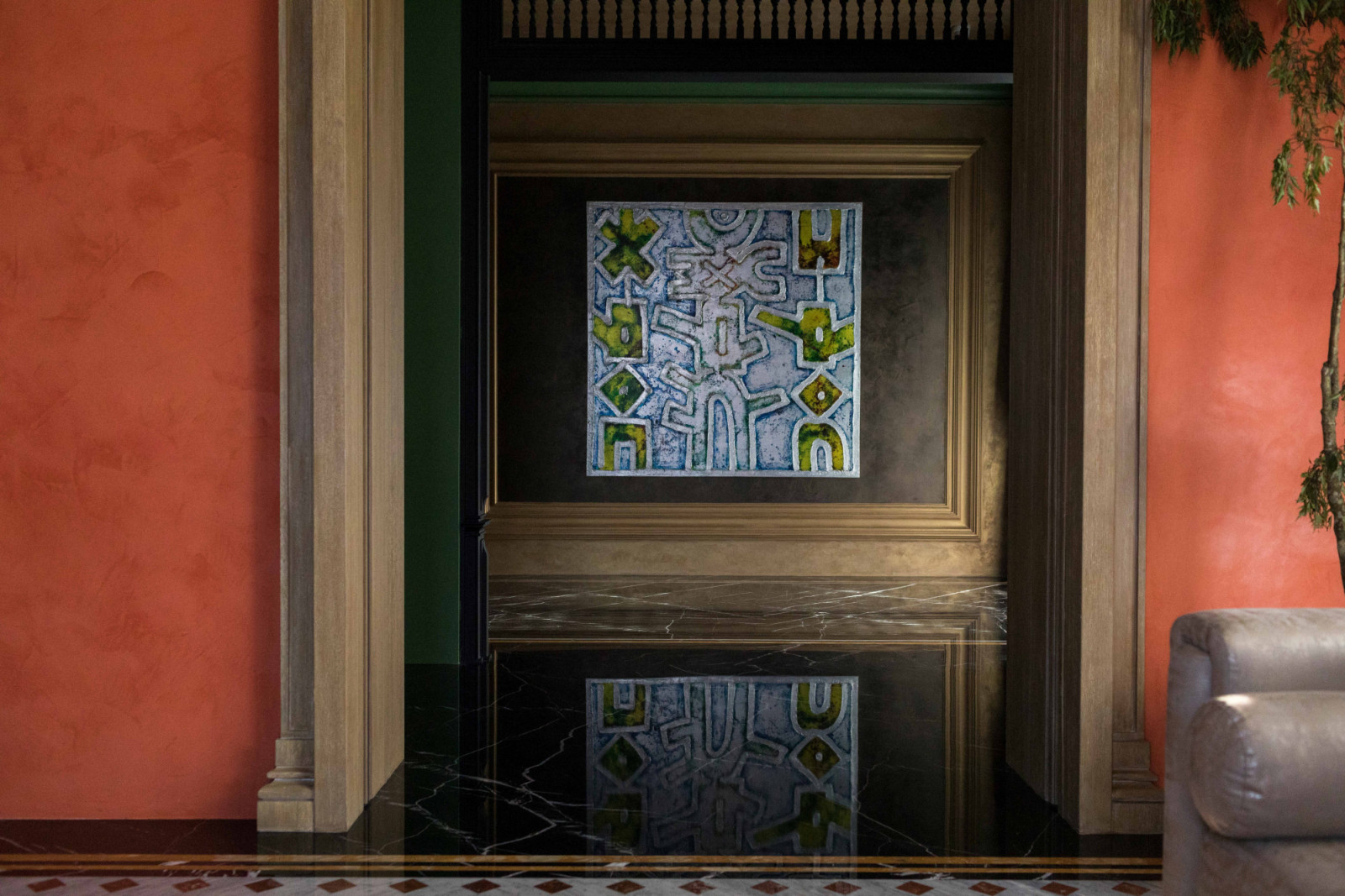 Modern artwork sits next orange walls, adding a contemporary layer to the neoclassical interiors