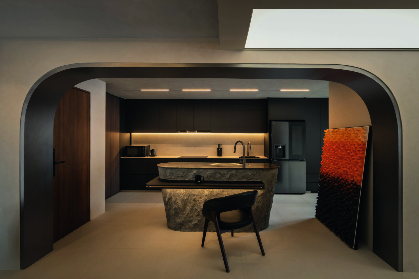 Framed by a curved portal, the kitchen is anchored by a sculptural stone island