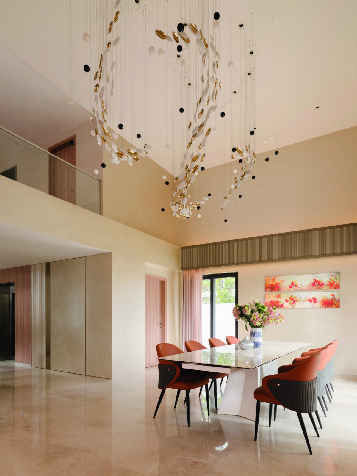 The double-height dining space is anchored by a custom lighting installation, its floating discs animating the neutral palette and warm leather seating below
