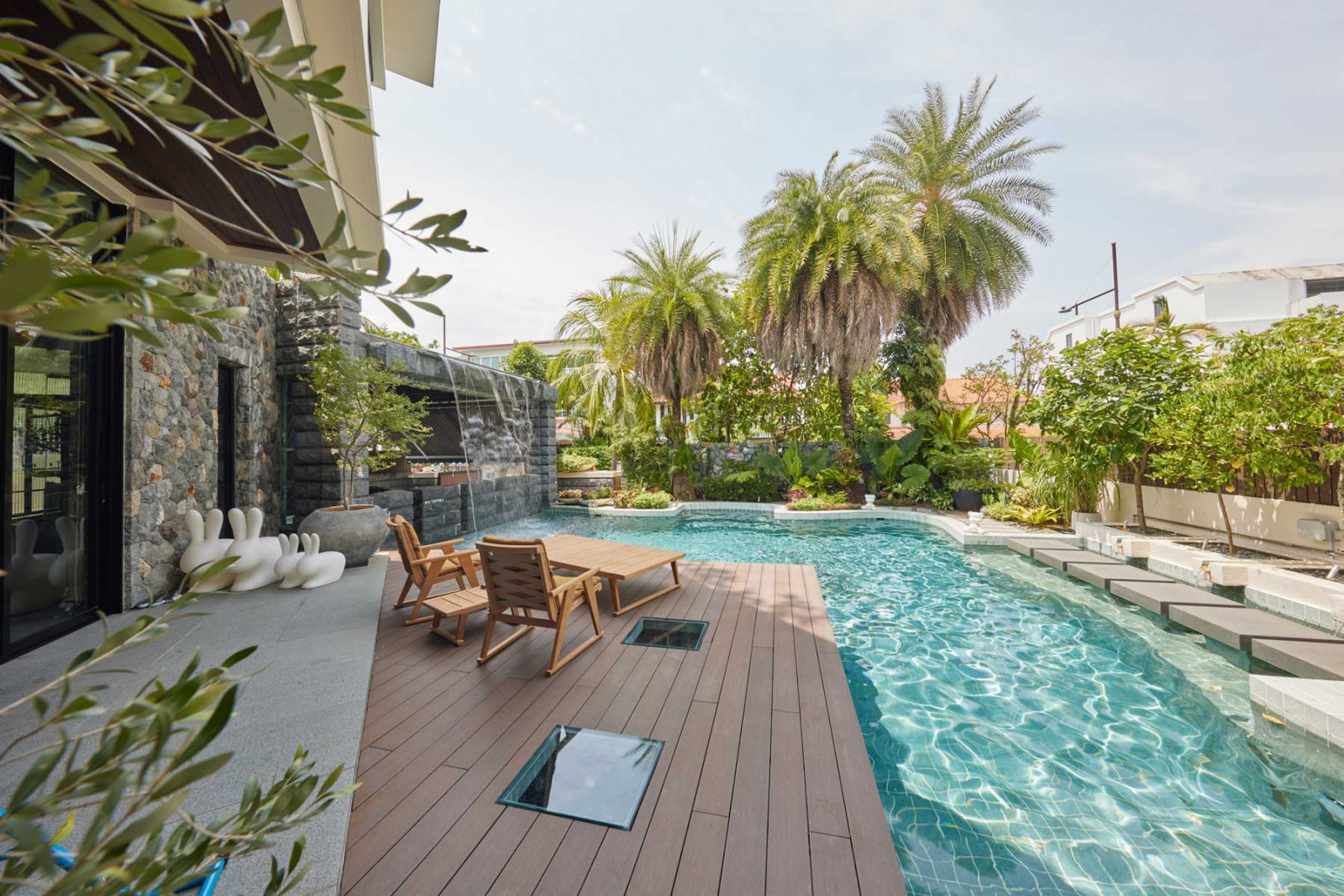 A view of the pool of the Opera Estate bungalow, punctuated by playful Qeeboo Rabbit chairs