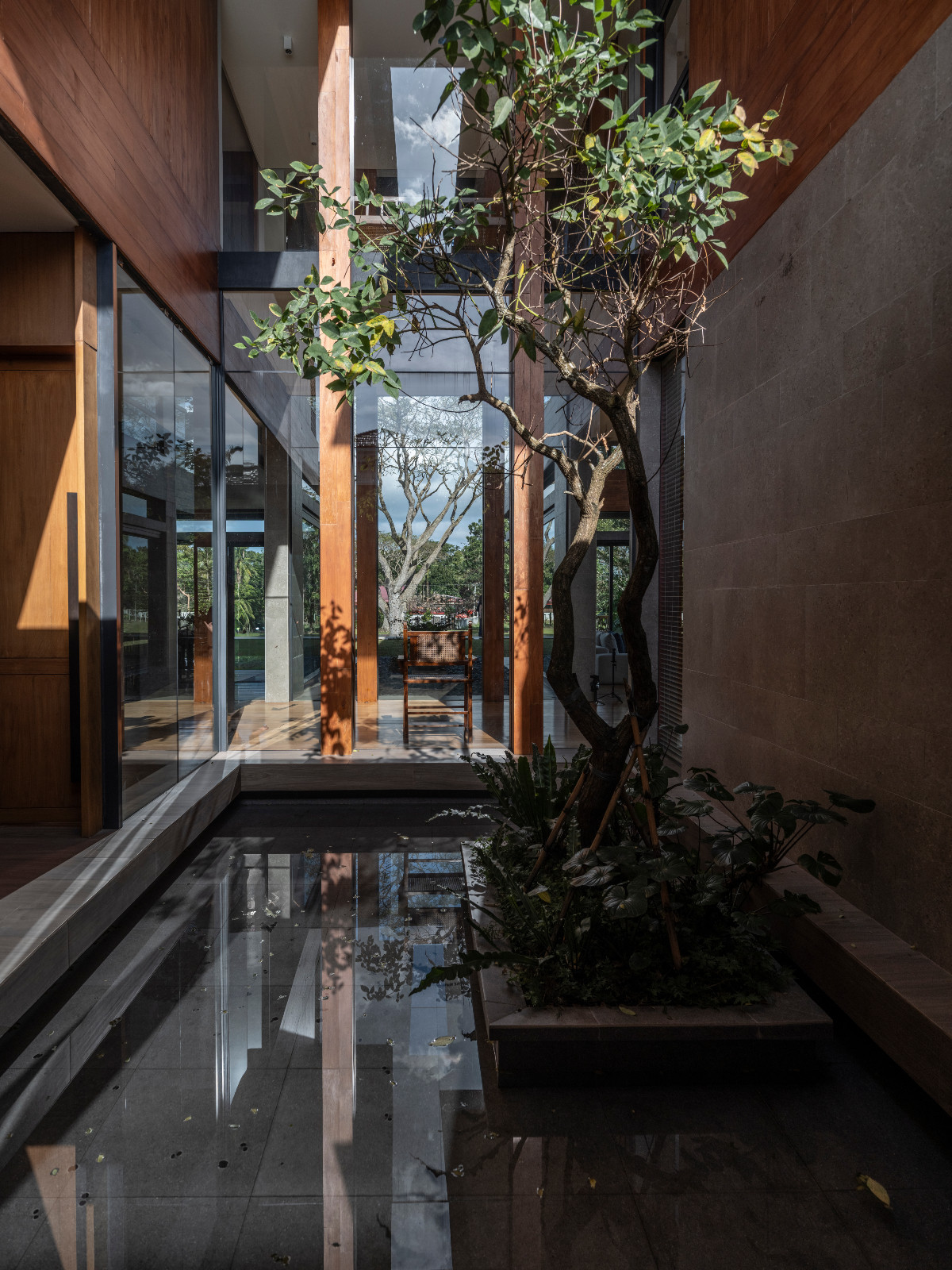 A reflective pool of water greets entrants to the Batangas, Philippines home designed by LYS Architecture, punctuated by greenery