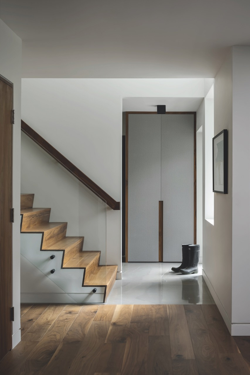 The entry hall incorporates floor-to-ceiling walnut millwork that aligns with the back facade of the pizza oven