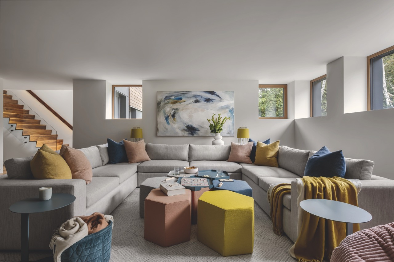 The lower-level recreation room features a custom sectional, Blu Dot ottomans and playful colours for the children