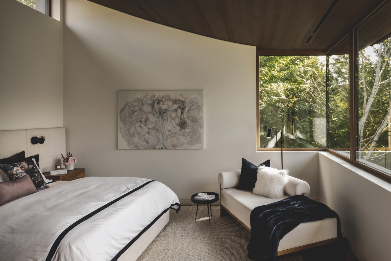 The primary bedroom features a custom bed, chaise longue, and cedar ceiling that extends through the main level