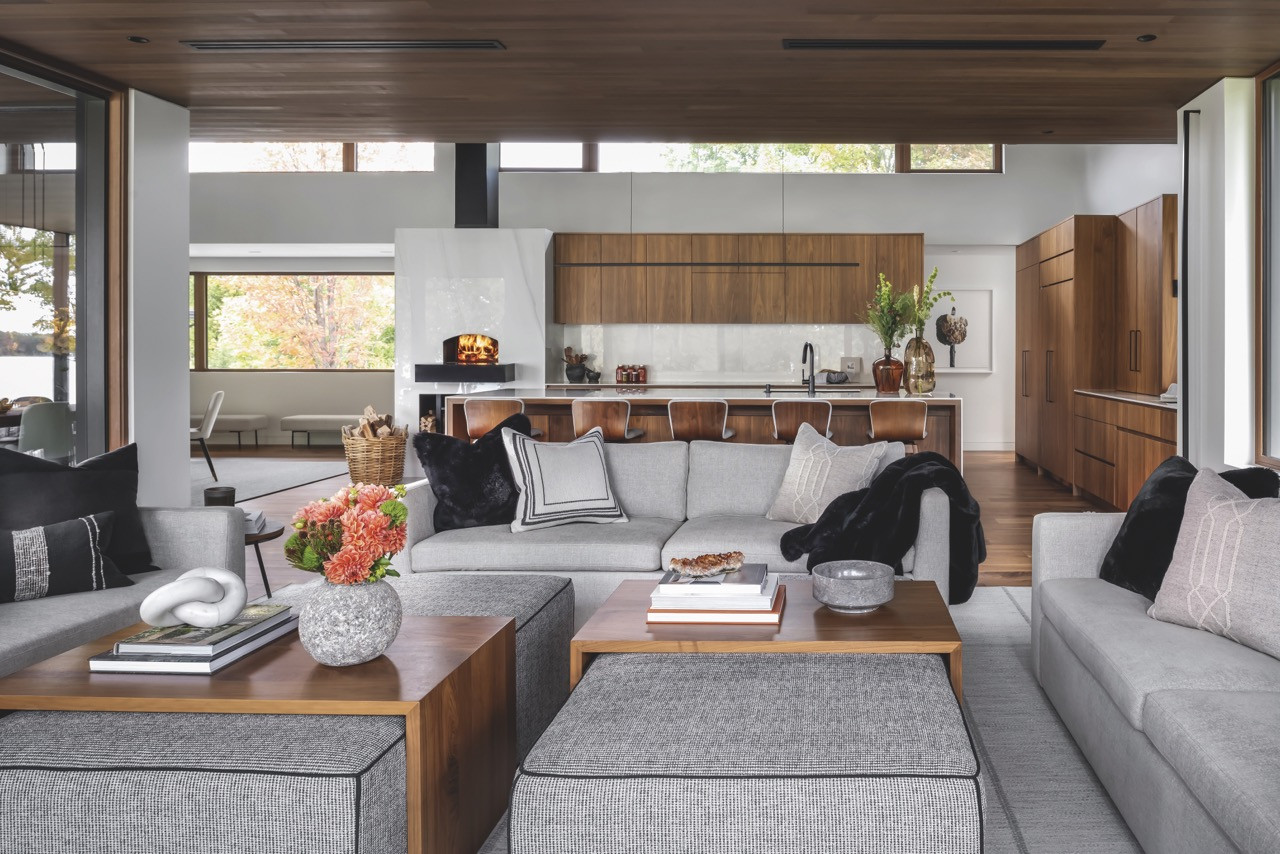 The open-plan living area features custom sofas and views towards the porcelain-clad pizza oven