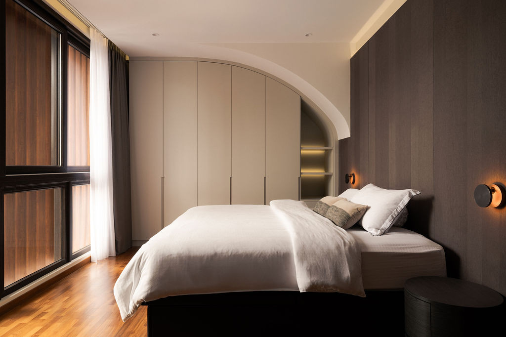 In the master bedroom, warm wood tones and built-in cabinetry are tucked neatly into a gentle arch, cleverly concealing the stair bulkhead that juts into the room.