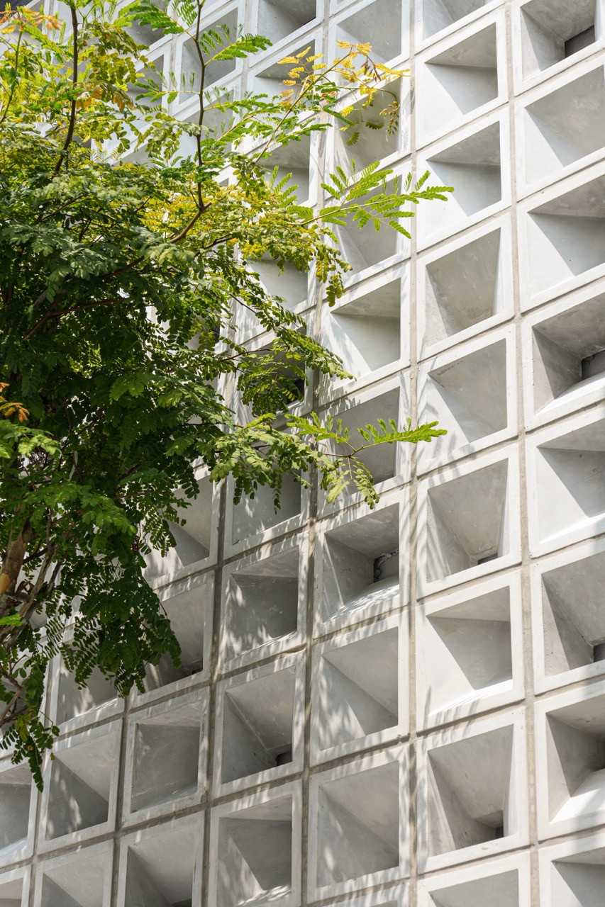 Close-up of the exterior deep-relief concrete screen wall with pyramidal block detailing, with a tree growing in front