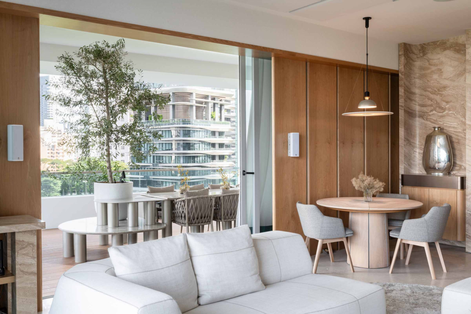A potted olive tree makes a bold statement beside the outdoor dining area