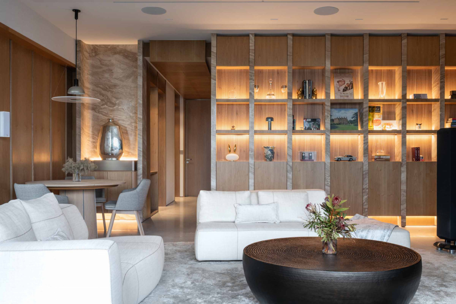 The Forme Congo coffee table anchors the living area, while full-height backlit shelving spans the length of a wall